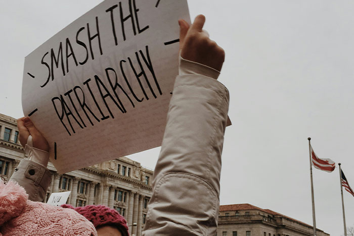 Protesters holding a smash the patriarchy sign, representing hard truths women realize and accept in life.