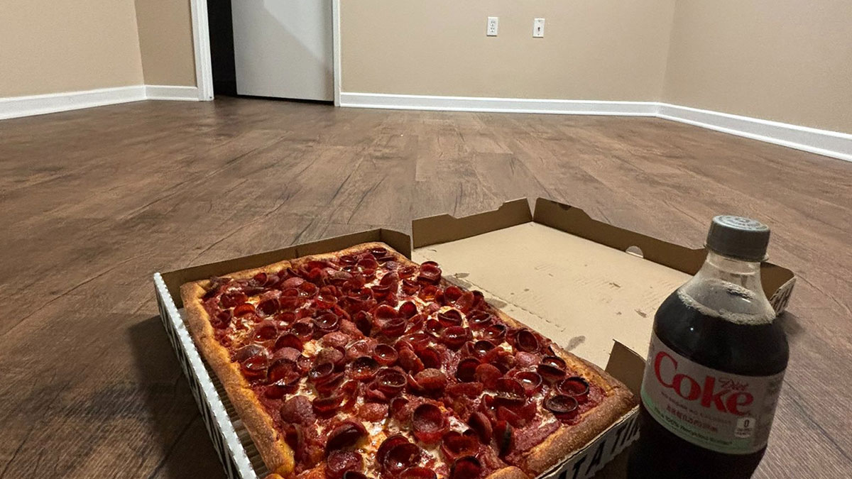 Pepperoni pizza and Diet Coke bottle on wooden floor in an empty room, a humorous tweet moment shared online.