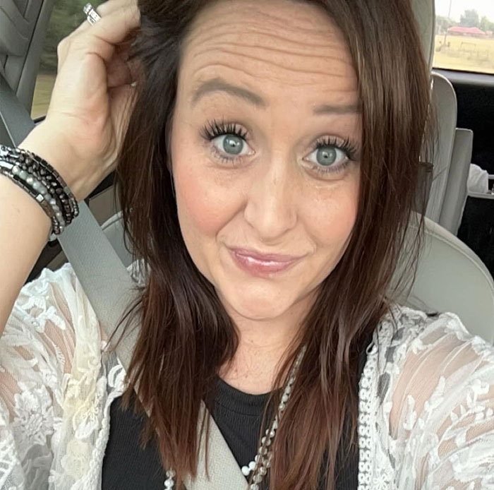 Young mom with brown hair sitting in car wearing seatbelt, highlighting story about restaurant's brutal mistake with drink.