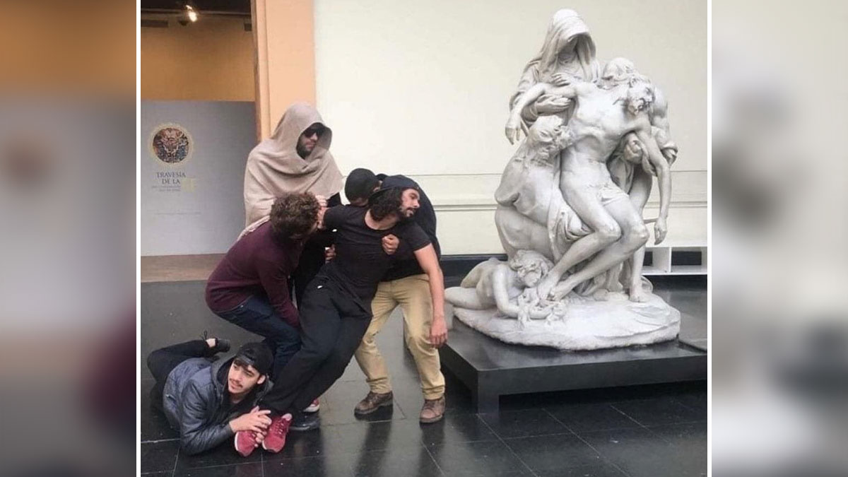 Group of people creatively imitating an iconic art sculpture by posing in similar dramatic and emotional positions indoors.