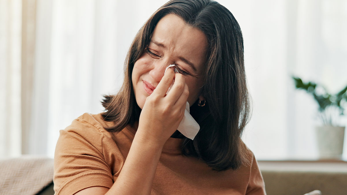 Woman wiping tears from her eyes, showing emotional distress related to being an ugly woman in a home setting.