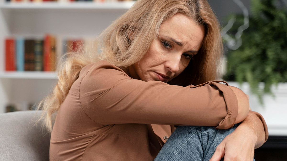 Sad woman hugging her knees, reflecting heartbroken emotions and pain from a past affair that still haunts her.