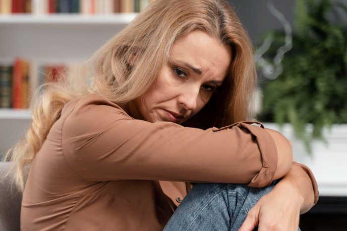 Heartbroken woman sitting alone with a sad expression, reflecting on past pain from husband's affair. Heartbroken woman sitting alone with a sad expression, reflecting on past pain from husband's affair.