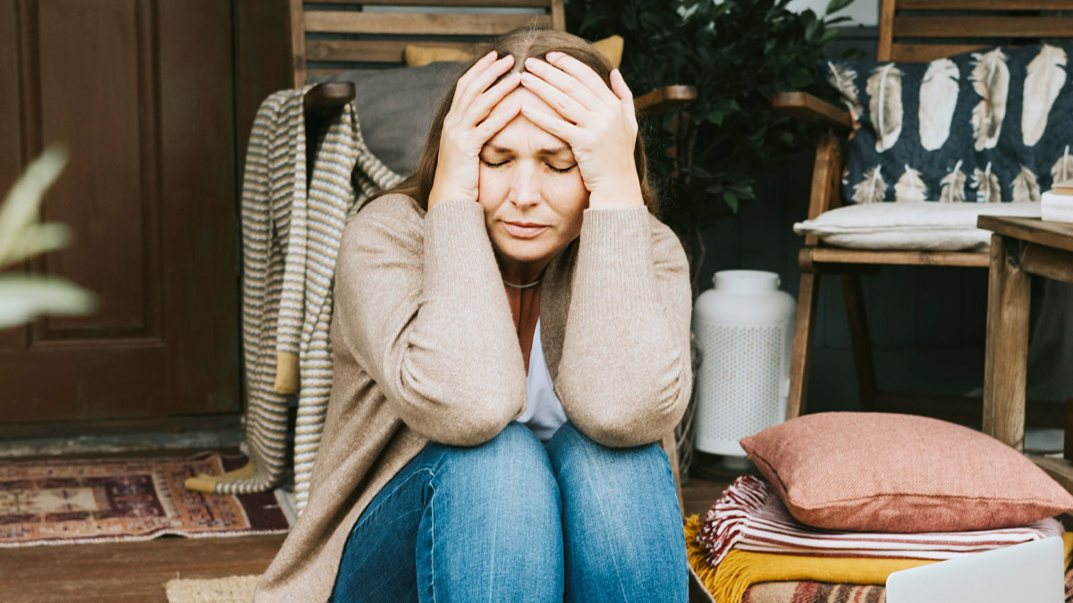 Stressed woman sitting on floor with hands on head, reflecting on business failure and refusing to have a boss.