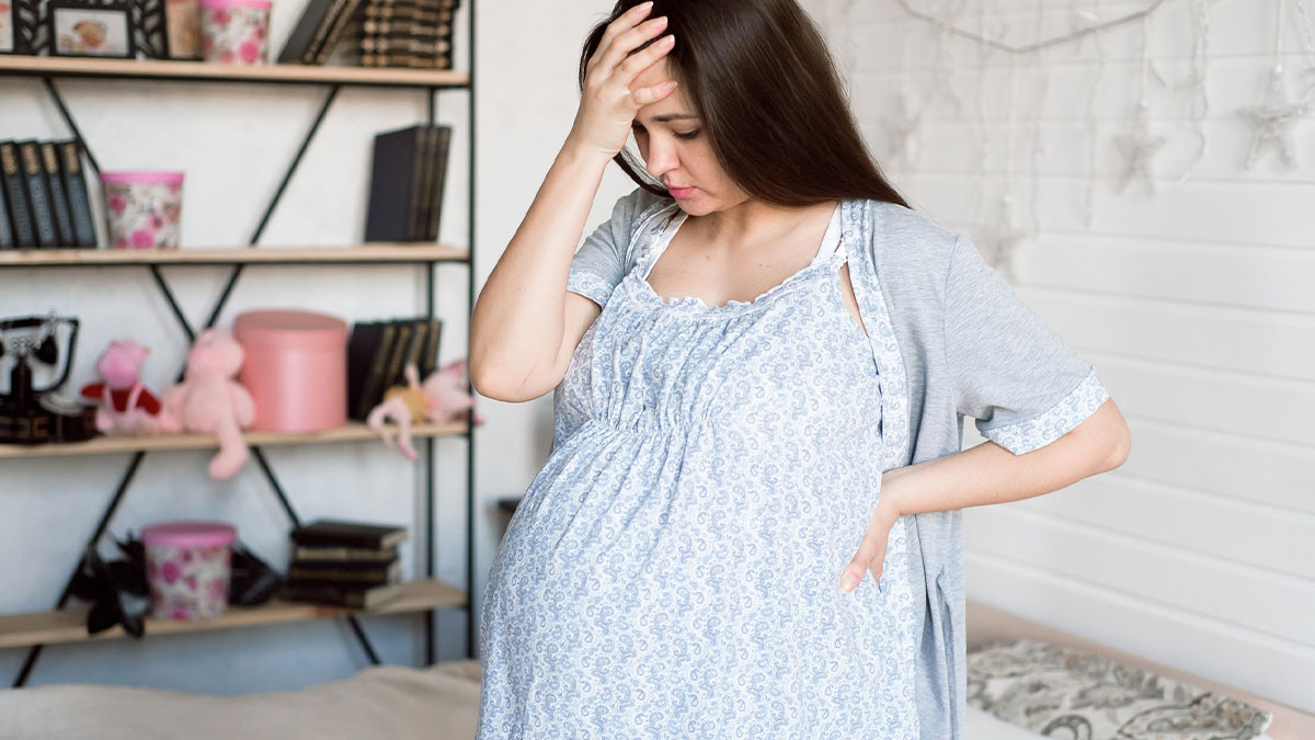Pregnant mom looking tired and stressed at home, representing mom-to-be feeling ignored while doing cardio with toddler and vacuum.