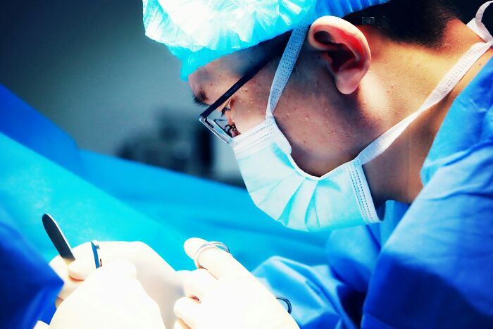 Surgeon in blue scrubs and mask focused on a procedure, illustrating worst first opinions doctors have encountered.
