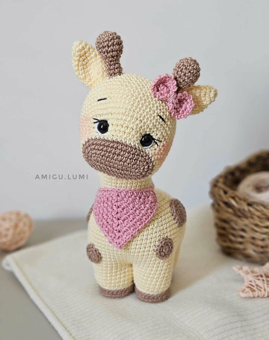 Crochet animal giraffe with big eyes, pink bow, and scarf, showcasing personality in handmade amigurumi style.