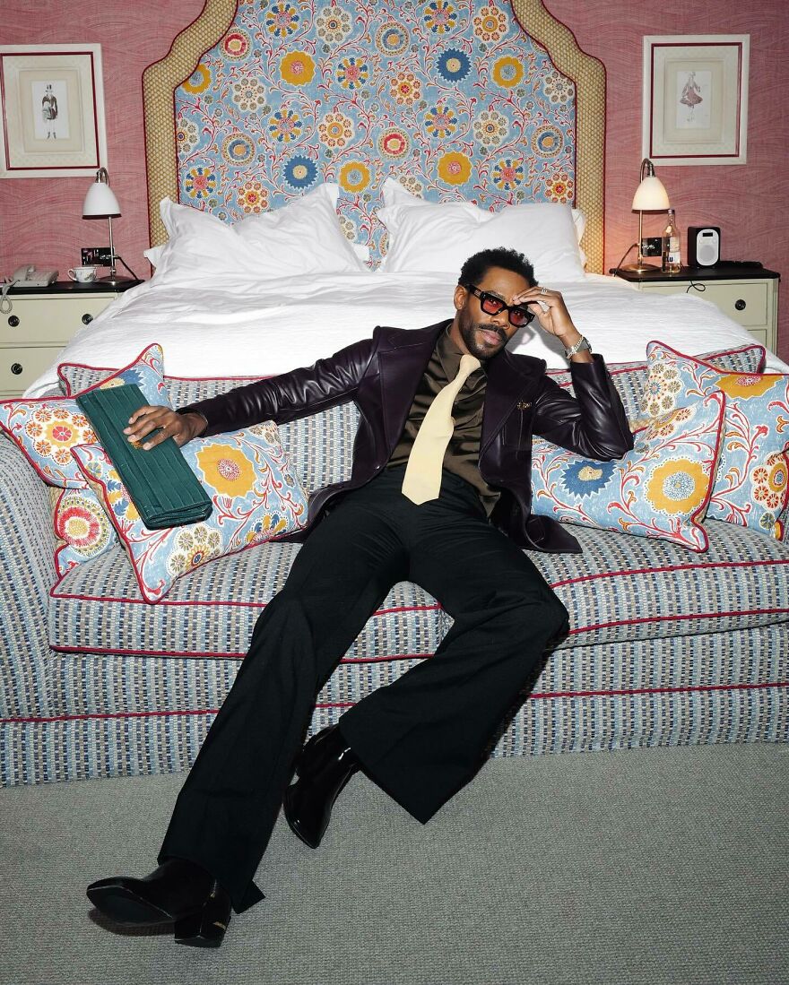 Stylish Colman Domingo posing confidently on a patterned sofa, embodying elegance and charm for the most handsome man 2025.