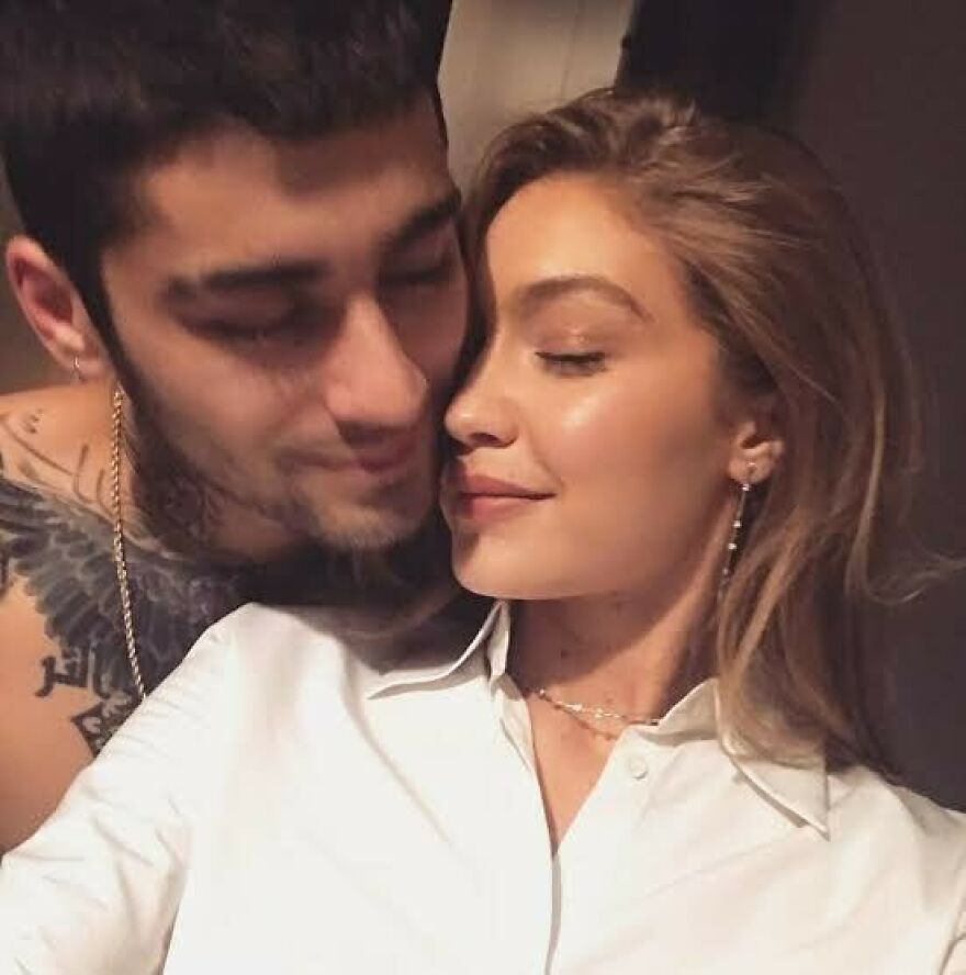 Gigi Hadid & Zayn Malik close together, sharing a tender moment in a warm, intimate setting.