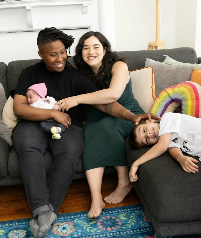 Two women sitting on a couch with a baby and child, highlighting a female professor's decision to stop dating men. Two women sitting on a couch with a baby and child, highlighting a female professor's decision to stop dating men.