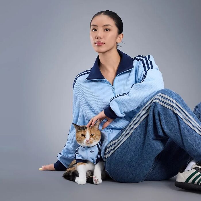 Woman and cat wearing matching blue sportswear outfits showcasing pet fashion collection looks.