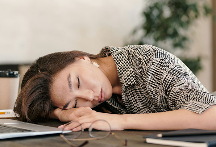 Woman resting head on table looking unwell, representing people who self-diagnosed correctly despite doctors' initial doubt.