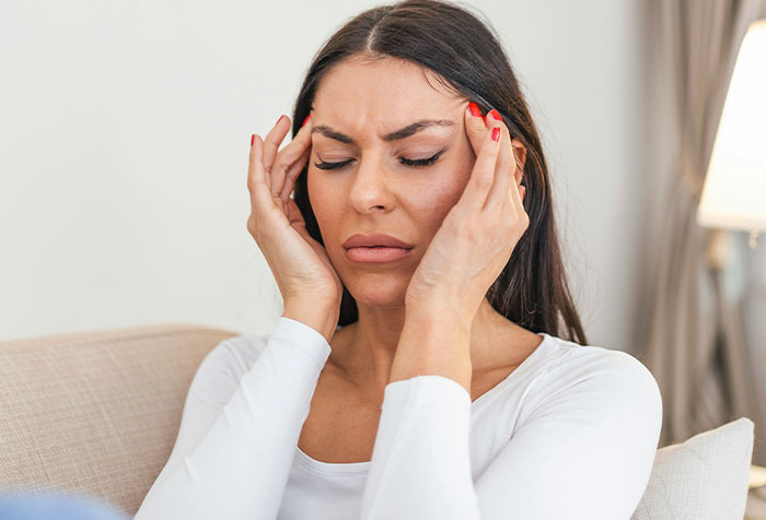 Woman holding her head in pain during a self-diagnosis moment, illustrating cases people diagnosed correctly themselves.