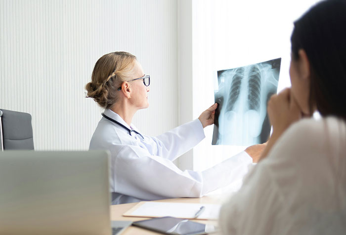 Doctor examining an X-ray while consulting a patient who self-diagnosed a medical condition accurately.