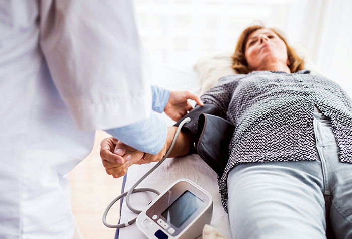 Doctor taking blood pressure of a woman lying down, highlighting cases of people self-diagnosing correctly despite initial doubt.