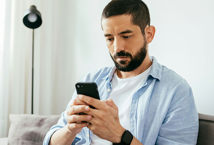 Man with beard using smartphone at home, representing people who self-diagnosed correctly despite initial doubts.