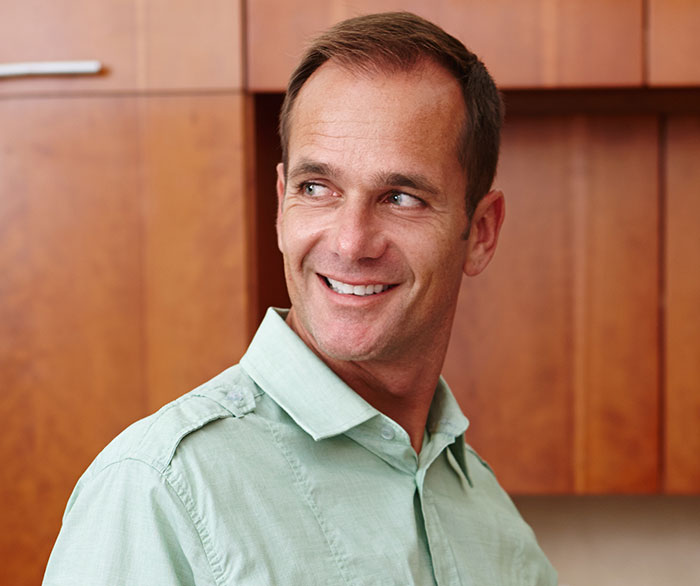 Smiling man in a light green shirt looking sideways in a home setting representing family conflict in relationships. Smiling man in a light green shirt looking sideways in a home setting representing family conflict in relationships.