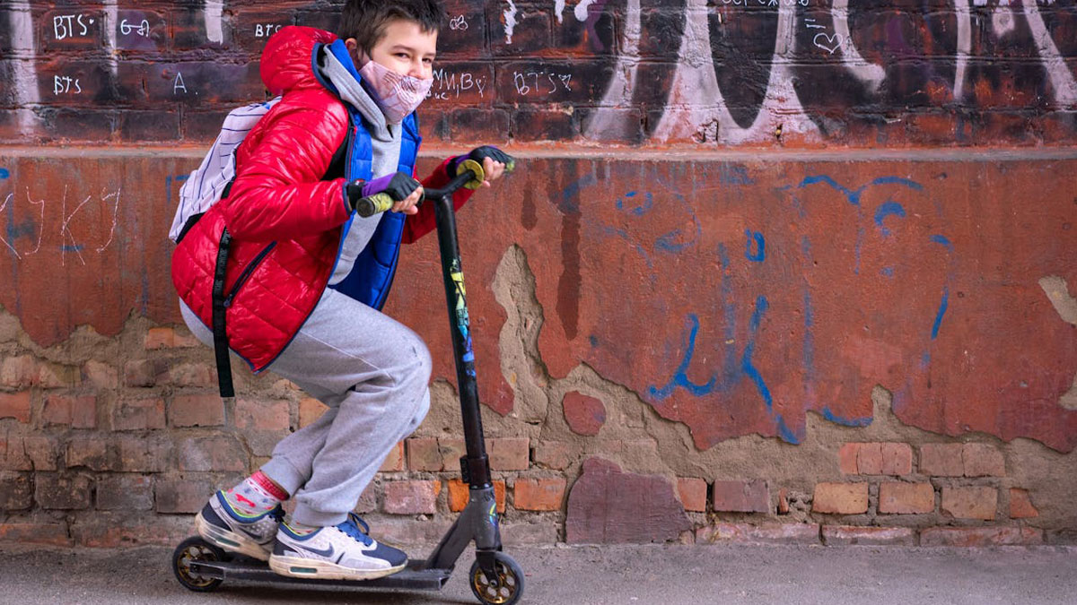 Boy riding scooter with backpack near graffiti wall, illustrating moments when karma came for people instantly.