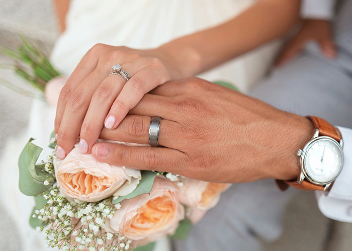 Close-up of hands with wedding rings over a bouquet, illustrating surprising facts about Rihanna slapped him.