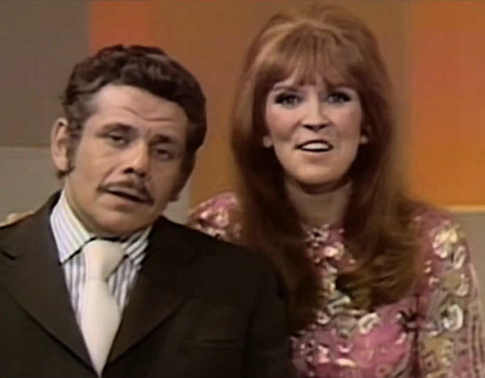 A man in a dark suit and tie with a woman in a floral dress, depicting Ben Stiller parenting mistakes and nepo baby criticism. A man in a dark suit and tie with a woman in a floral dress, depicting Ben Stiller parenting mistakes and nepo baby criticism.