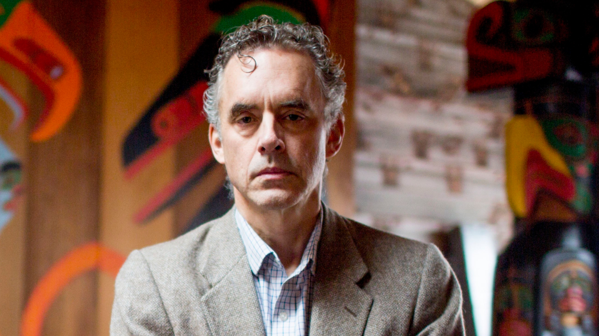 Jordan Peterson in a brown jacket, serious expression, with Native art in the background highlighting net worth figures.