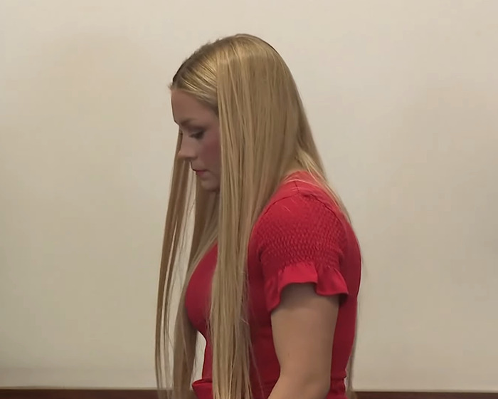Woman with long blonde hair in a red shirt looking down during the Laken Snelling baby case courtroom proceedings. Woman with long blonde hair in a red shirt looking down during the Laken Snelling baby case courtroom proceedings.