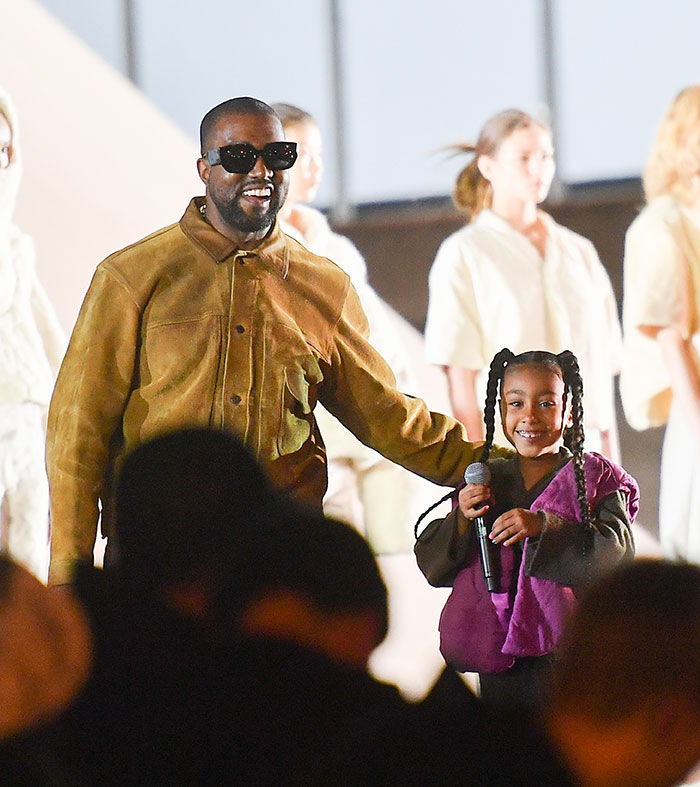 Kanye West standing with daughter North West holding a microphone during a public event amid online life concerns. Kanye West standing with daughter North West holding a microphone during a public event amid online life concerns.
