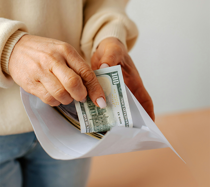 Hands placing cash into an envelope symbolizing rent extortion and deceit in a relationship context. Hands placing cash into an envelope symbolizing rent extortion and deceit in a relationship context.