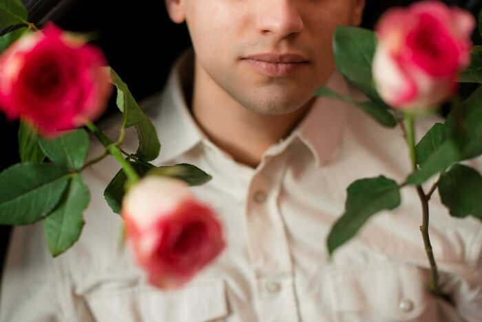 Man holding red roses with a sad expression, illustrating a painful table for two moment turning into table for one.