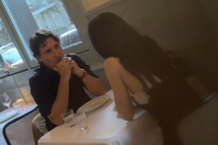 Katy Perry and shirtless Justin Trudeau sitting and talking closely at a cozy indoor table setting. Katy Perry and shirtless Justin Trudeau sitting and talking closely at a cozy indoor table setting.