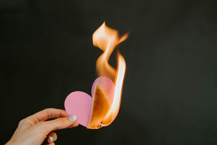 Hand holding a burning paper heart symbolizing relationship advice and challenges every couple should know.