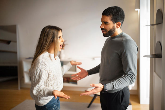 Couple arguing indoors, showing frustration and stress, illustrating conflict caused by homeless friend mooching off them.