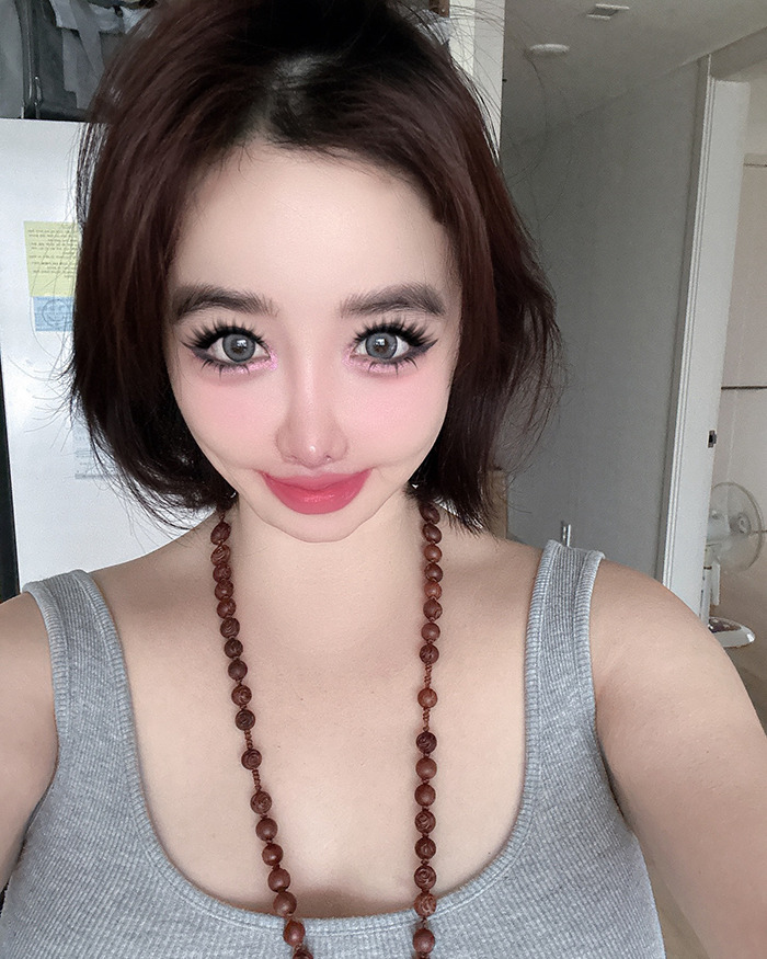 K-Pop icon Park Bom wearing a gray tank top and necklace, showing her drastic plastic surgery transformation. K-Pop icon Park Bom wearing a gray tank top and necklace, showing her drastic plastic surgery transformation.