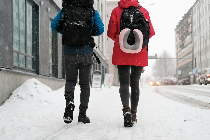 Two people walking on a snowy city street wearing backpacks, illustrating disturbing things folks were told later realized as creepy.