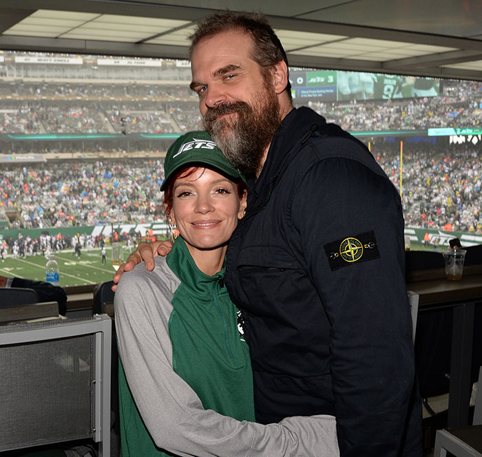 Lily Allen and David Harbour hugging at a stadium during a football game, showing a close moment together. Lily Allen and David Harbour hugging at a stadium during a football game, showing a close moment together.