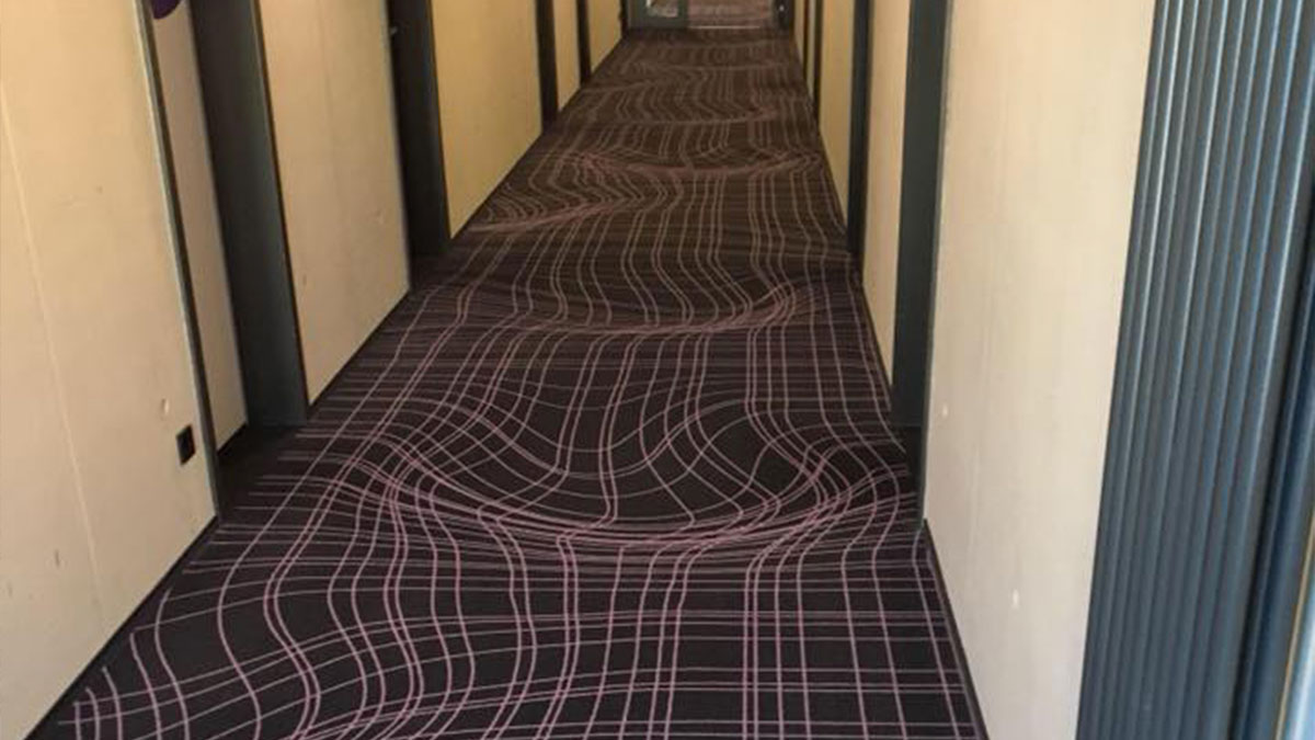 Hallway with carpet creating an optical illusion of undulating waves in a beautiful yet unnerving liminal space.