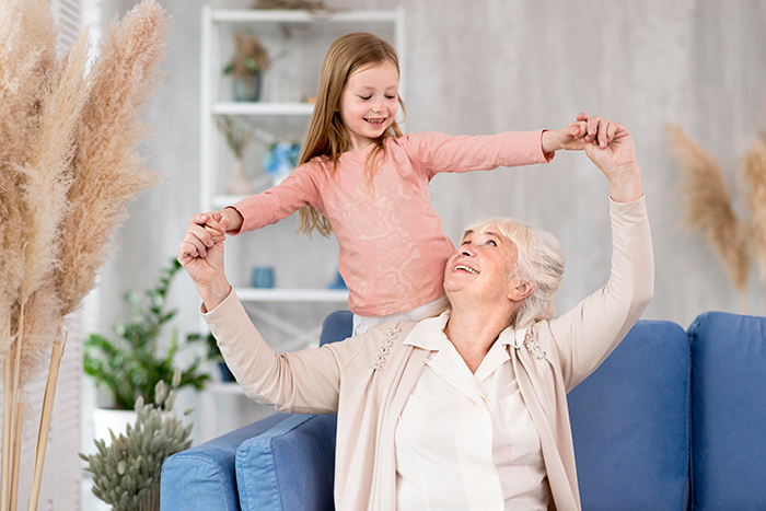 Elderly woman and young girl smiling and holding hands in a bright room, contrasting stepdaughters disown stepmother drama. Elderly woman and young girl smiling and holding hands in a bright room, contrasting stepdaughters disown stepmother drama.
