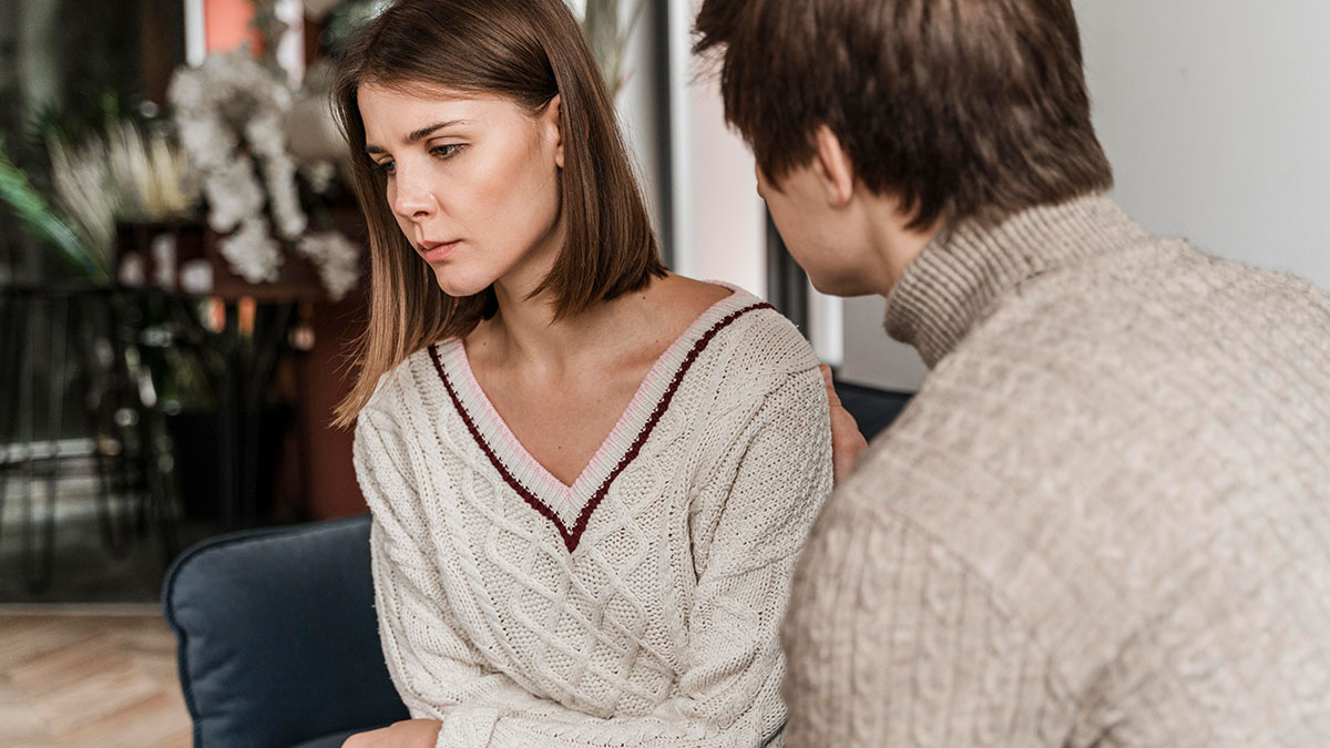 Woman looks worried while her boyfriend gently talks to her about saving niblings from foster care and their future plans.
