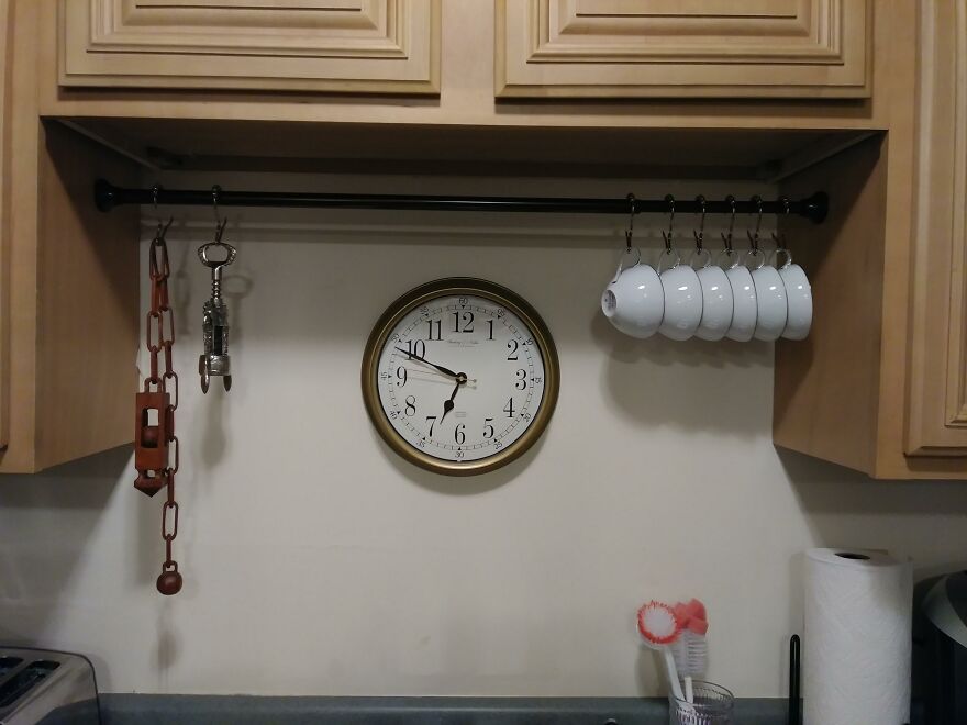 Kitchen organization hacks showing cups and tools hanging on a rod to maximize home storage space efficiently.
