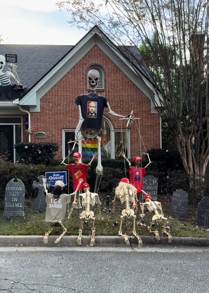 Elaborate anti-MAGA Halloween display with skeleton puppets wearing political shirts and red hats in a front yard. Elaborate anti-MAGA Halloween display with skeleton puppets wearing political shirts and red hats in a front yard.