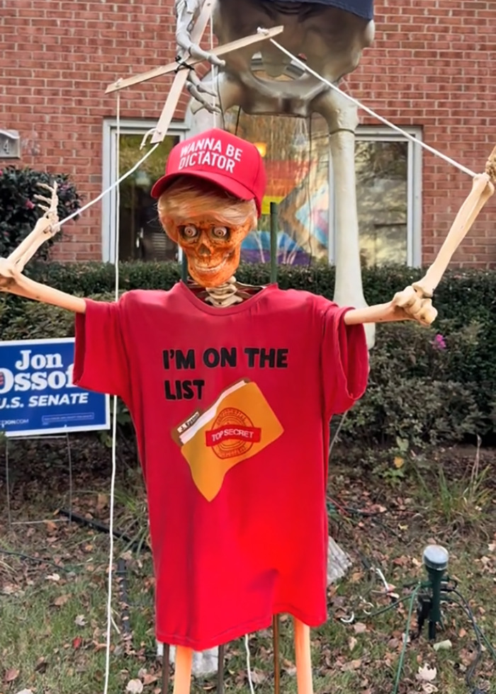 Skeleton Halloween display wearing a red shirt and hat as part of an elaborate anti-MAGA Halloween decoration. Skeleton Halloween display wearing a red shirt and hat as part of an elaborate anti-MAGA Halloween decoration.
