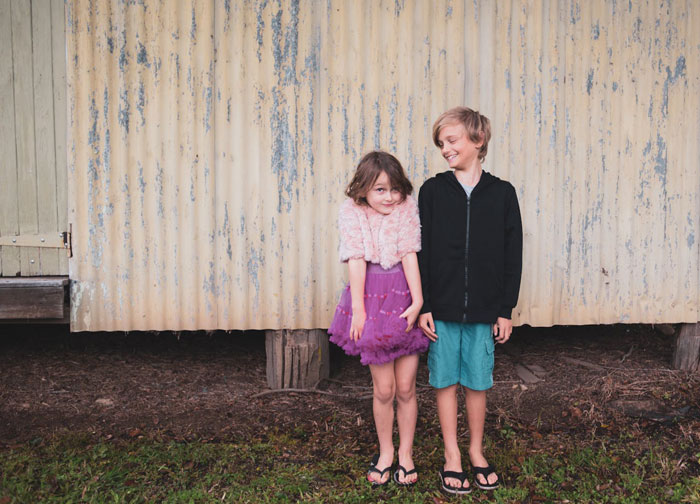 Two children standing outside, a girl in a purple dress and a boy in a black hoodie, representing sibling dynamics. Two children standing outside, a girl in a purple dress and a boy in a black hoodie, representing sibling dynamics.