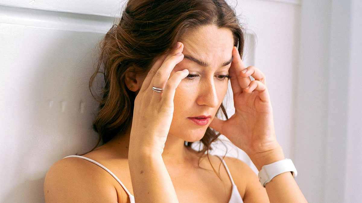 Woman feeling stressed and frustrated, holding her temples, reflecting on brother-in-law wedding conflict and family tension.
