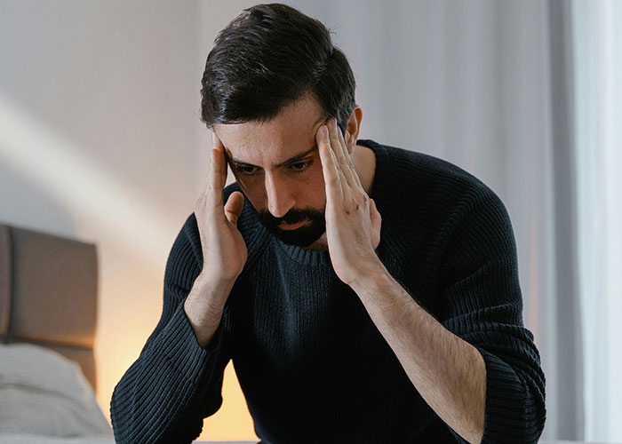 Man in black sweater looking stressed and holding his head, illustrating conflict with brother-in-law and wedding issues.