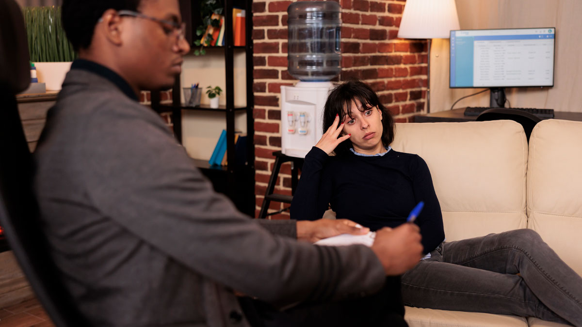 Woman showing frustration during therapist session in a cozy office, highlighting coupleu2019s therapy and relationship conflict.