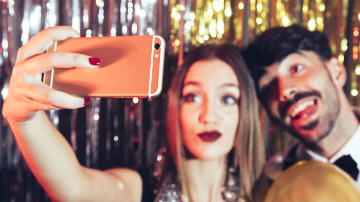 Young woman and man taking a selfie at a party, related to boss wife claim affair and innocent worker topics. Young woman and man taking a selfie at a party, related to boss wife claim affair and innocent worker topics.