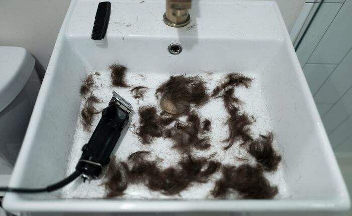 Hair clippings and an electric trimmer left in a sink, illustrating shocking things popular kids did in school that turned them into outcasts.