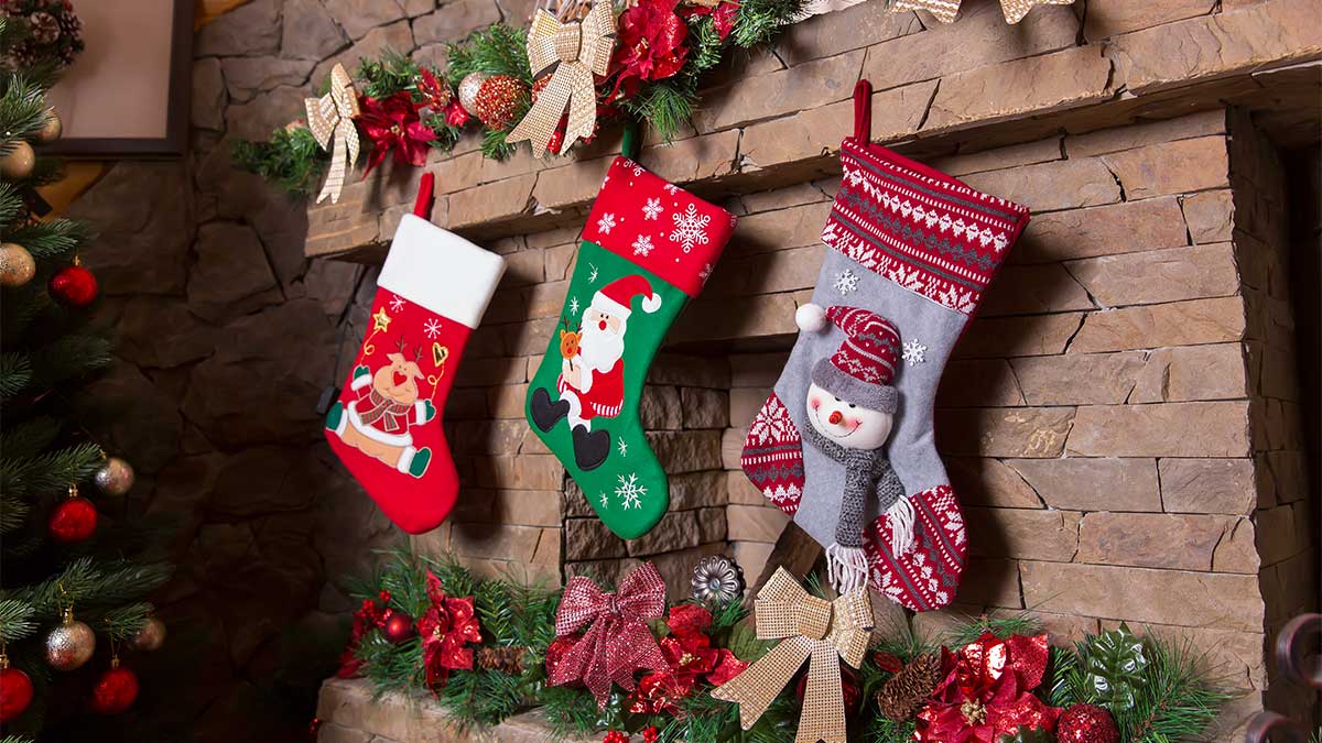 Christmas stockings hanging on a stone fireplace with festive garlands and holiday decorations in a cozy living room setting