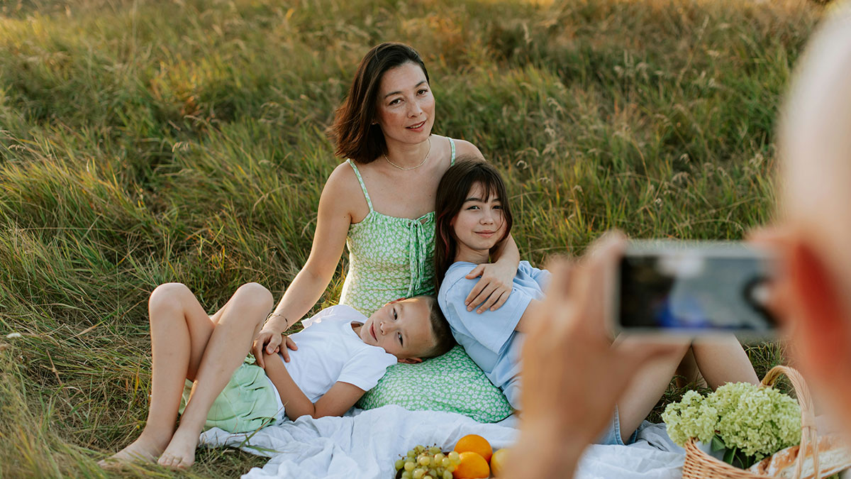 Woman and children having an outdoor photoshoot in a field, capturing moments of an overbearing MIL family conflict.