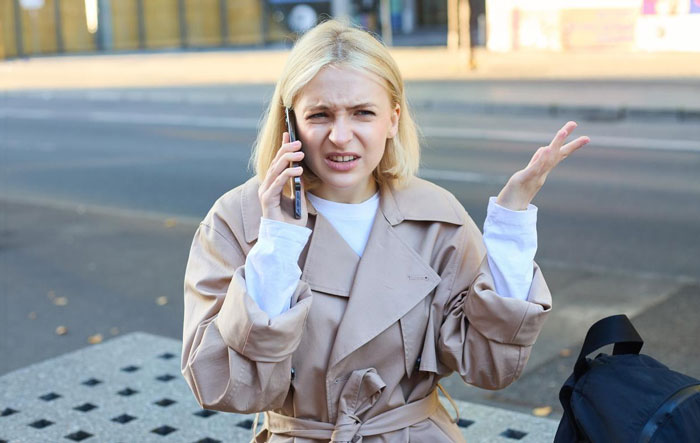 Young woman looking annoyed while talking on phone, upset by nonstop calls from mystery number, confused outdoors. Young woman looking annoyed while talking on phone, upset by nonstop calls from mystery number, confused outdoors.